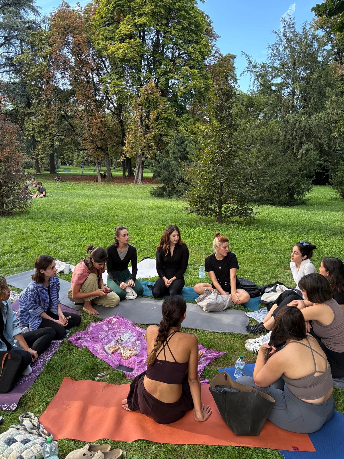 Youva community circle gathered on mats in a Milan park
